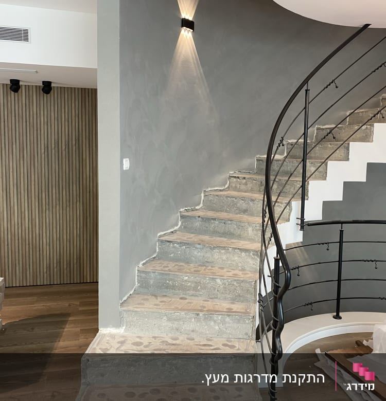 מדרגות עץ מעוקלות עם מעקה מתכת שחור